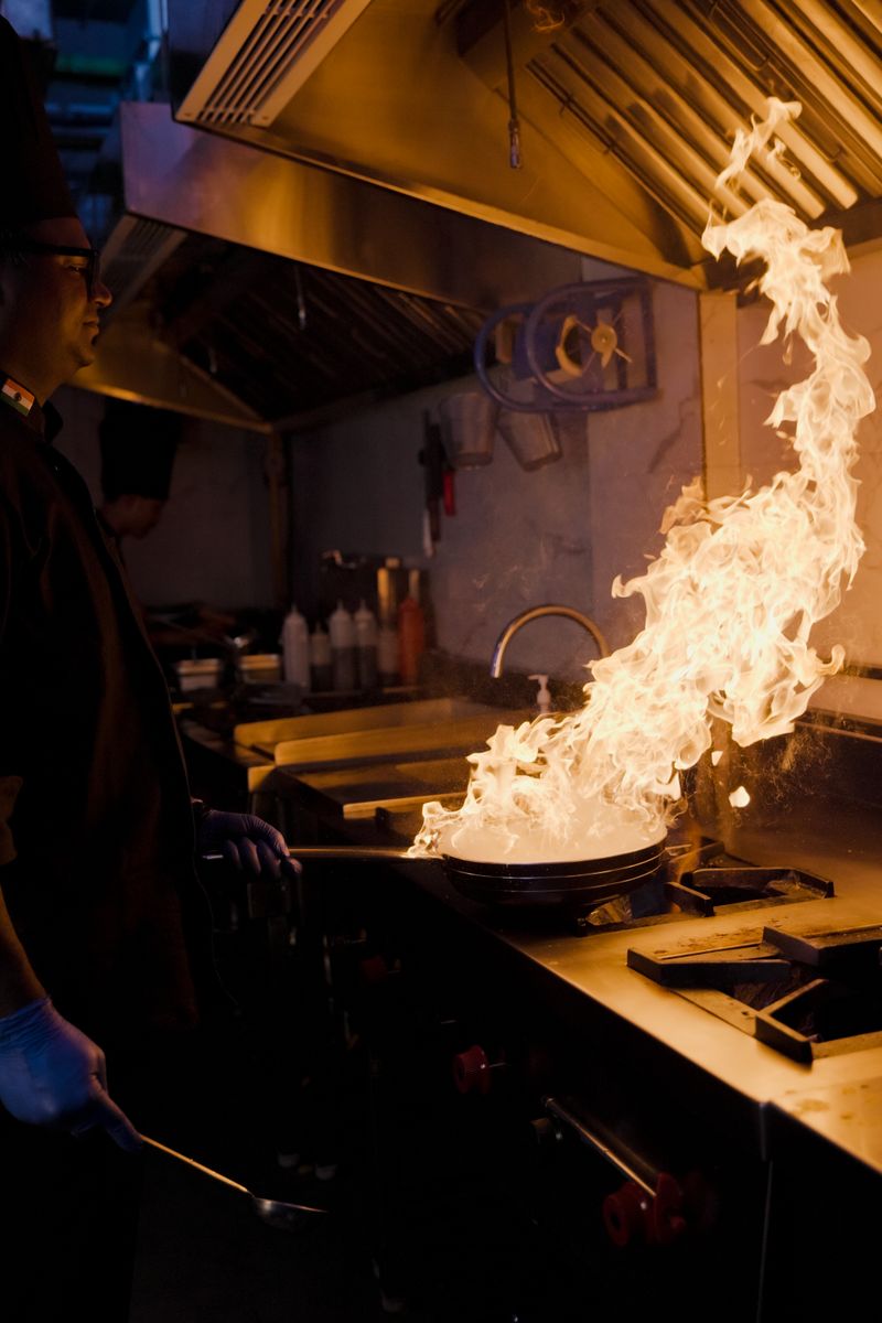 Chef cooking over flames in the Spice Route kitchen